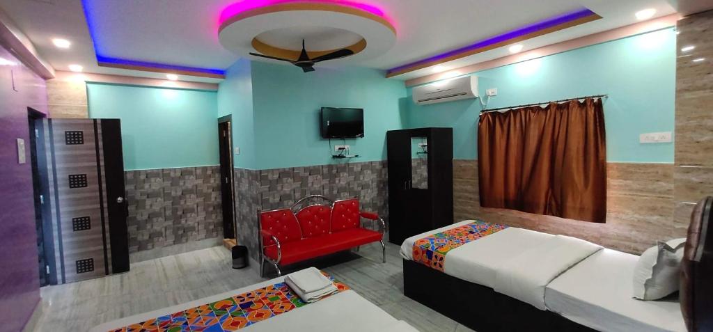 a room with two beds and a red chair at Hotel Nest Park Street in Kolkata