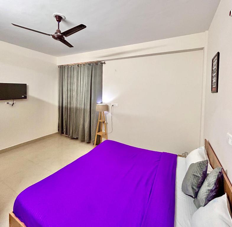een slaapkamer met een bed met een paarse deken bij Stargaze Inn - Comfy Stays in Greater Noida