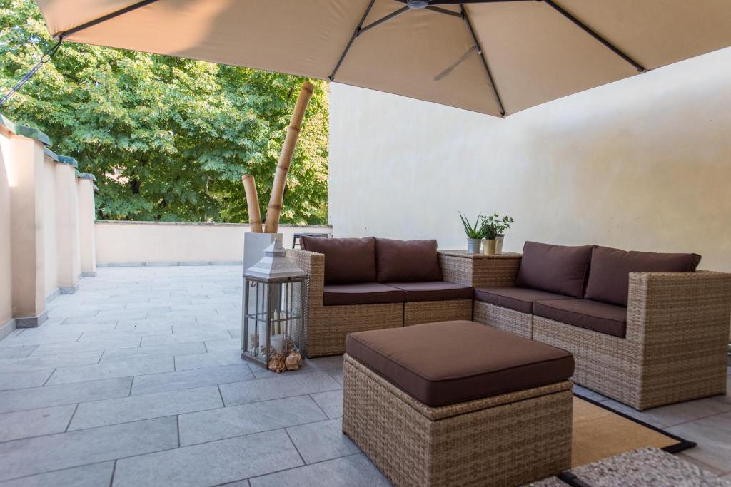 patio z 2 kanapami i parasolem w obiekcie Luna Sul Tetto w mieście Carpi