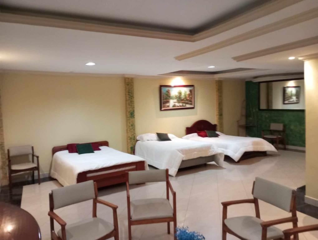 a hotel room with two beds and chairs at Suite amplia y elegante in Loja