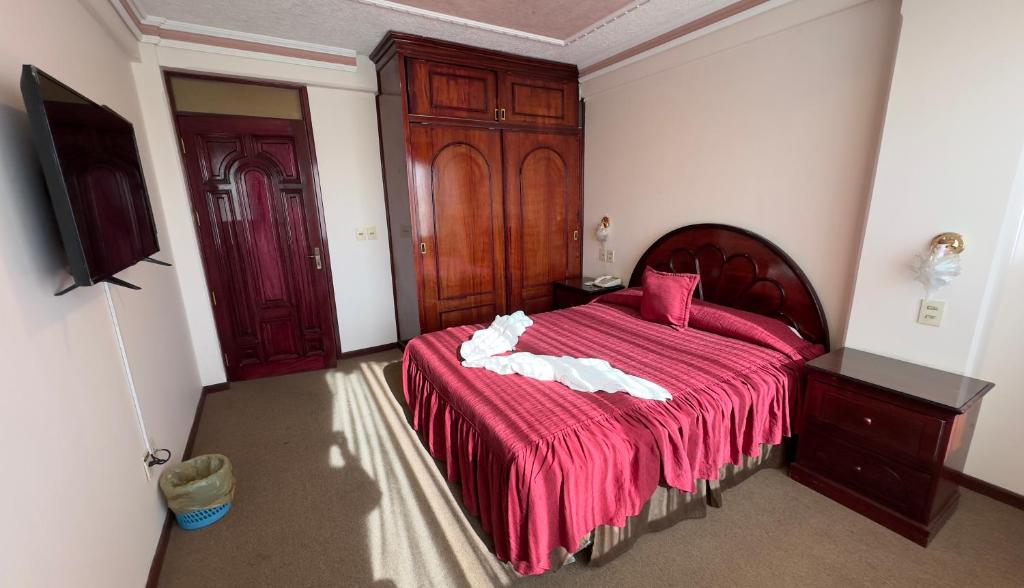 a bedroom with a large bed with a red blanket at Hotel V I D GALAX Resort in Oruro