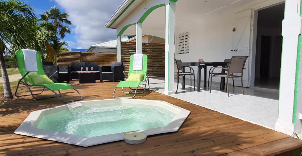 a hot tub on a deck with chairs and a table at LES KOKI VILLA MOJITO in Saint-François