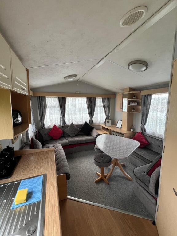 a living room with a couch and a table in a caravan at Cornish Dreams in Newquay