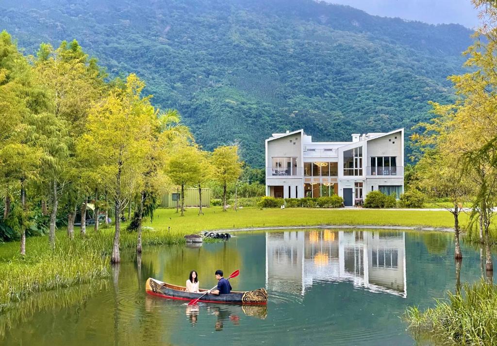 dos personas en una canoa en un lago frente a una casa en 靜樹湖民宿Jing Shuhu B&B, en Shuhu