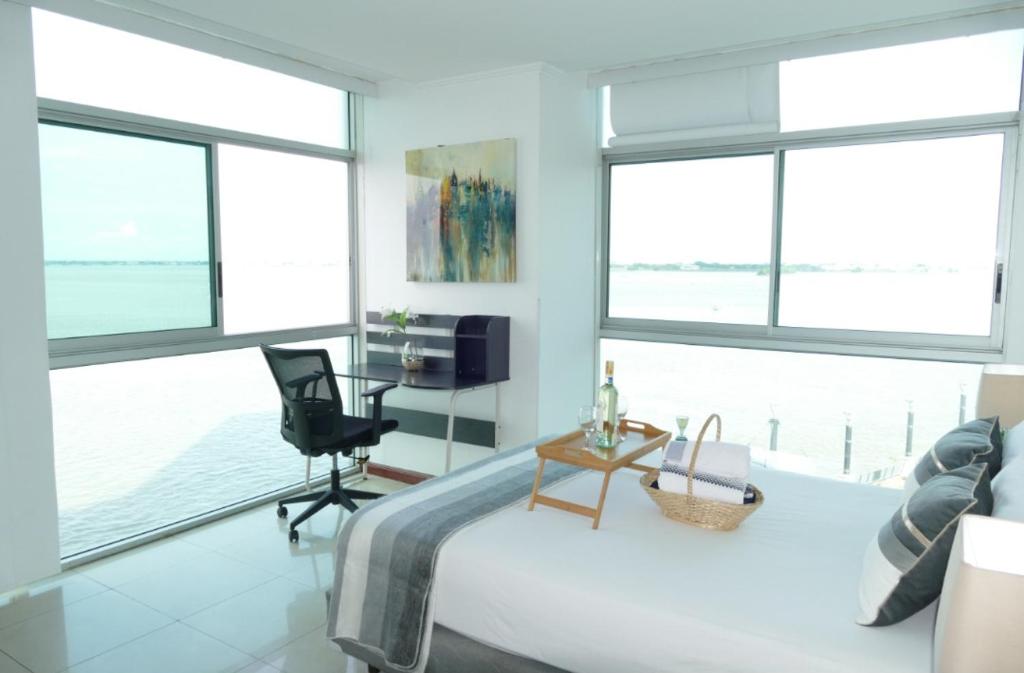 a bedroom with a bed and a desk and windows at Ecusuites Resort Riverfront Family Dept Santa Ana Gye in Guayaquil