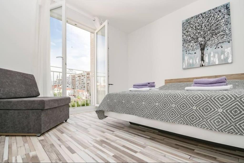 a white bedroom with a bed and a chair at LUX Apartment in Split