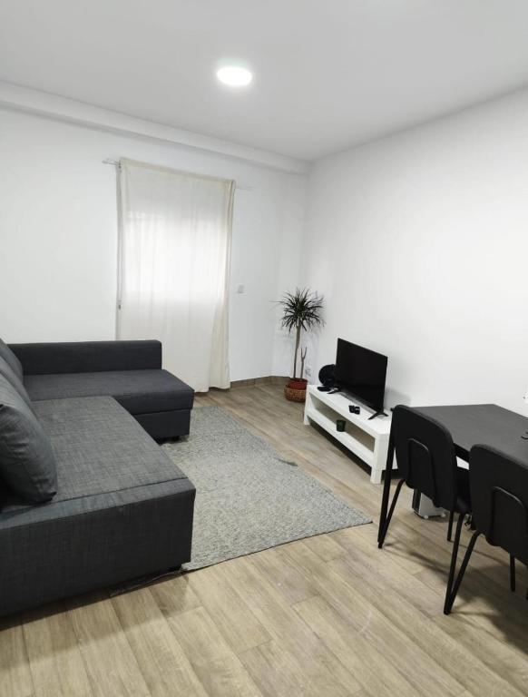 een woonkamer met een bank, een tafel en een tv bij Casa Aqueduto in Lissabon