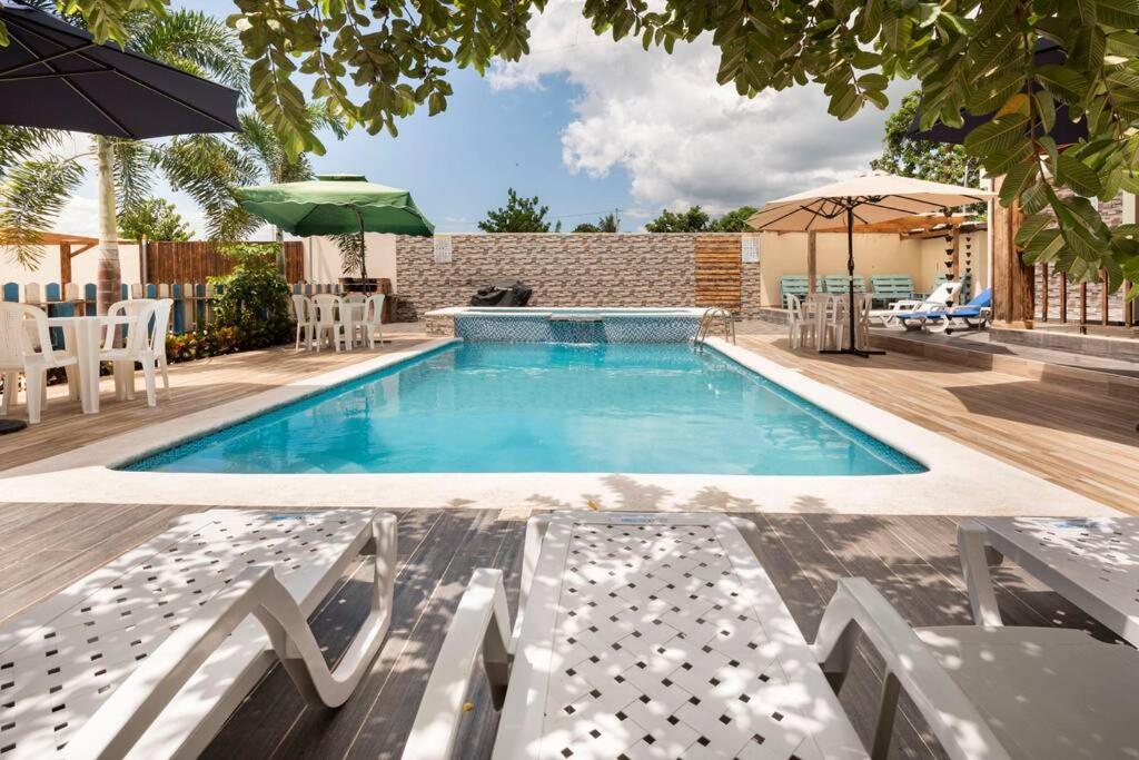 a swimming pool with chairs and an umbrella at Encantadora Villa con piscina. in Santiago de los Caballeros