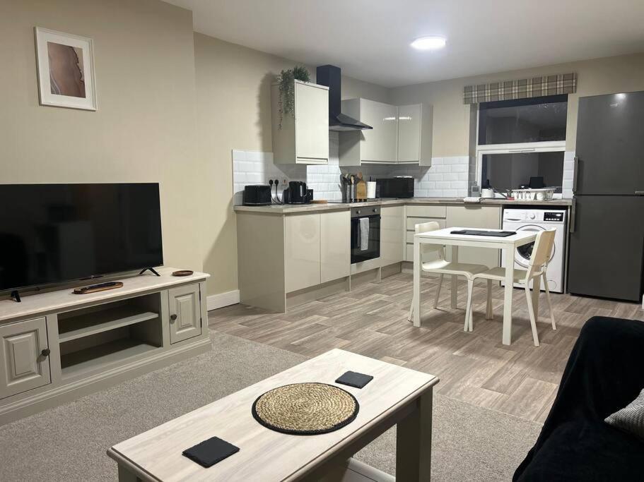 a living room with a kitchen with a tv and a table at Comfortable & Spacious Apartment in Stoke on Trent