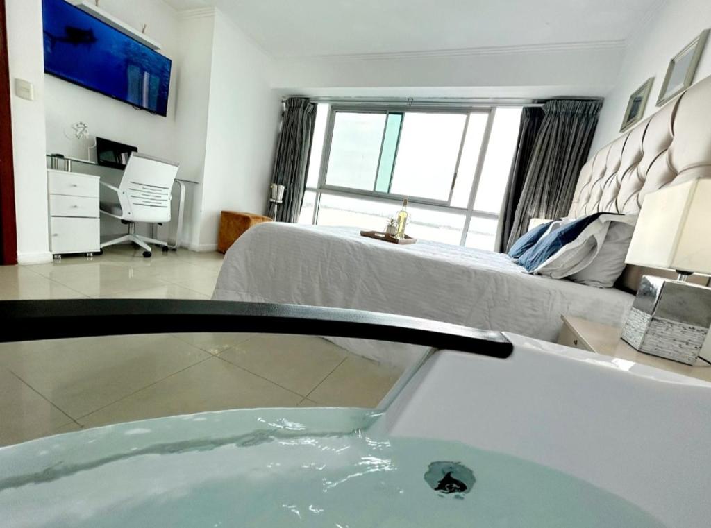 a bathroom with a tub and a bedroom with a bed at Ecusuites Riverfront One Vista al Río Jacuzzi Hidro in Guayaquil