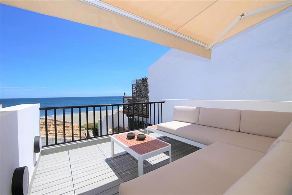 een woonkamer met een bank en een balkon met uitzicht op de oceaan bij Beachhouse GALORE in Estepona