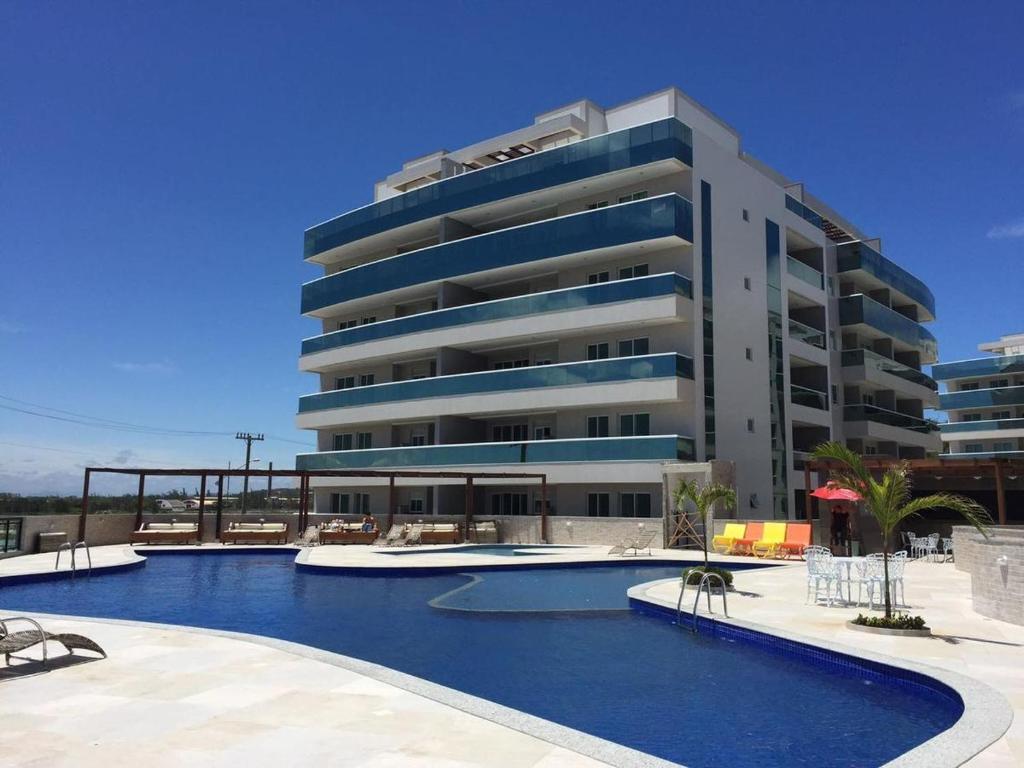 a hotel with a swimming pool in front of a building at Le Bon Vivant - Praia Grande - Arraial do Cabo in Arraial do Cabo