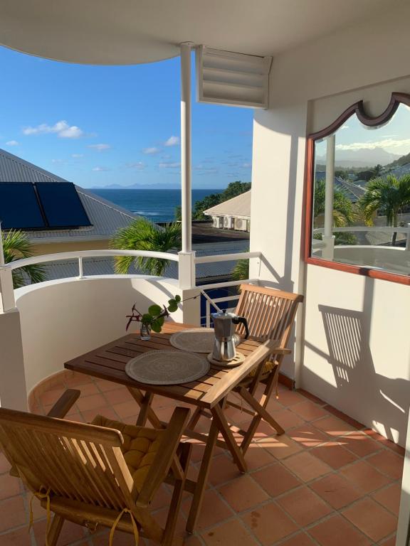 una mesa y sillas en un balcón con vistas al océano en Studio Entre Terre et Mer, Tartane, Martinique, en La Trinité