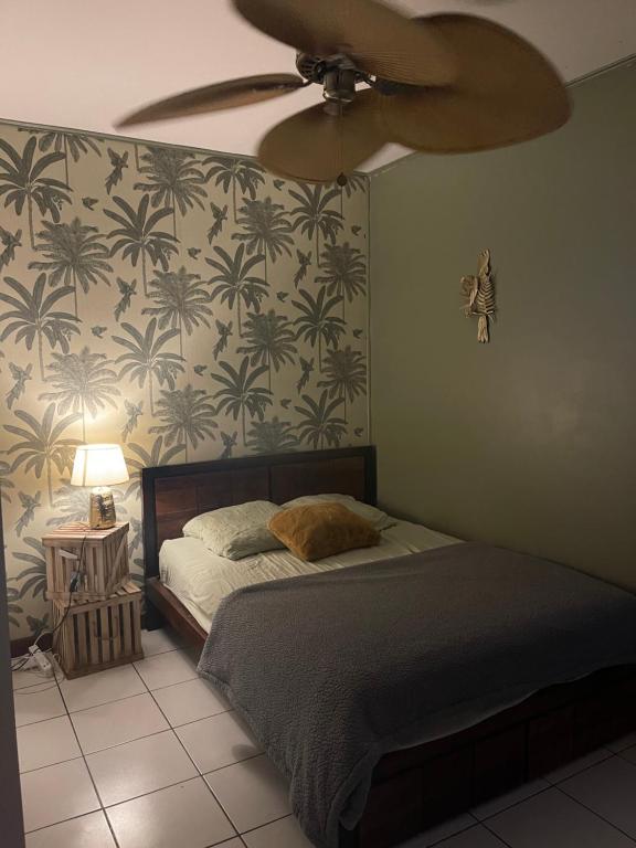 - une chambre avec un lit et un ventilateur de plafond dans l'établissement Ti kaz coco, à Saint-Leu