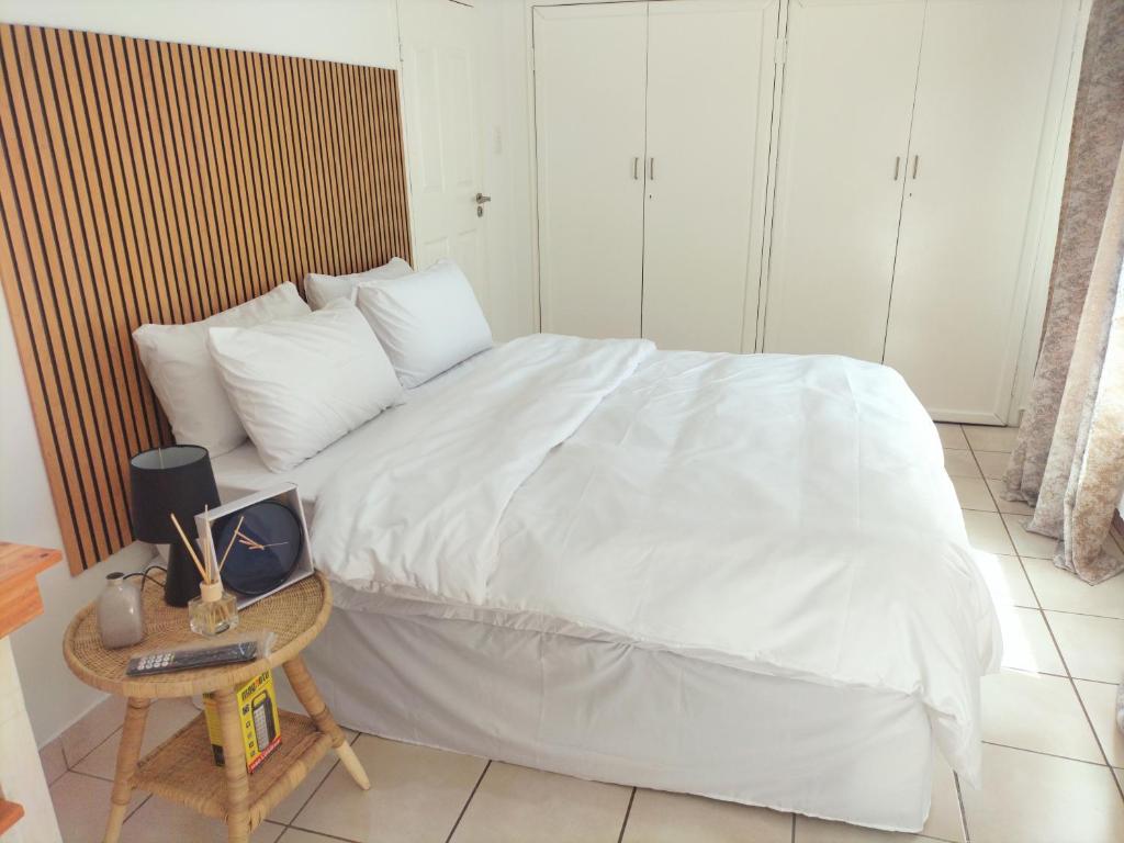 a bedroom with a white bed and a table with a laptop at The protea nest in Johannesburg