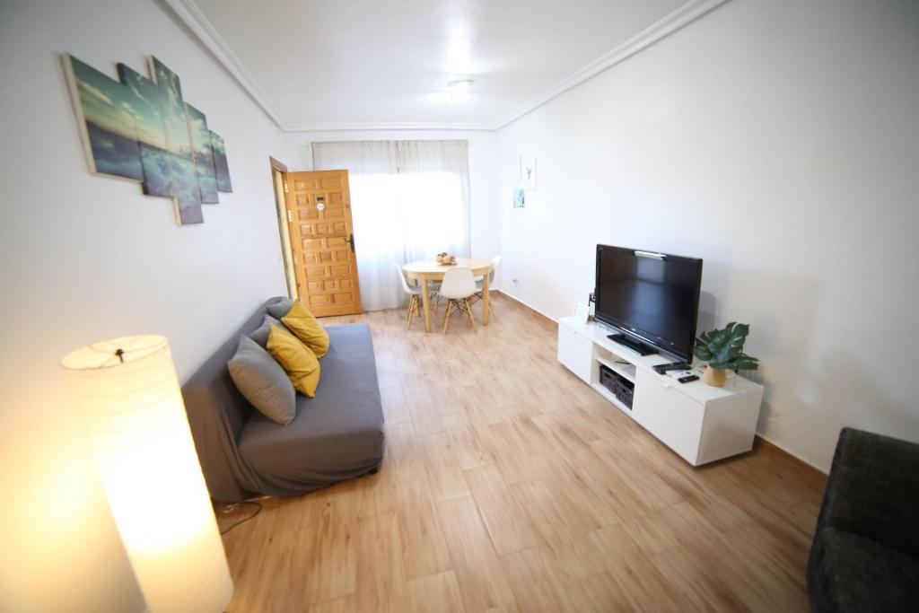 a living room with a couch and a flat screen tv at Casa de playa, cerca de todo in Los Narejos