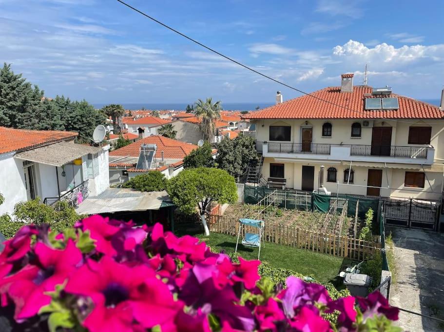 a view of a house with pink flowers in the foreground at Marithea apartment in Pefkochori
