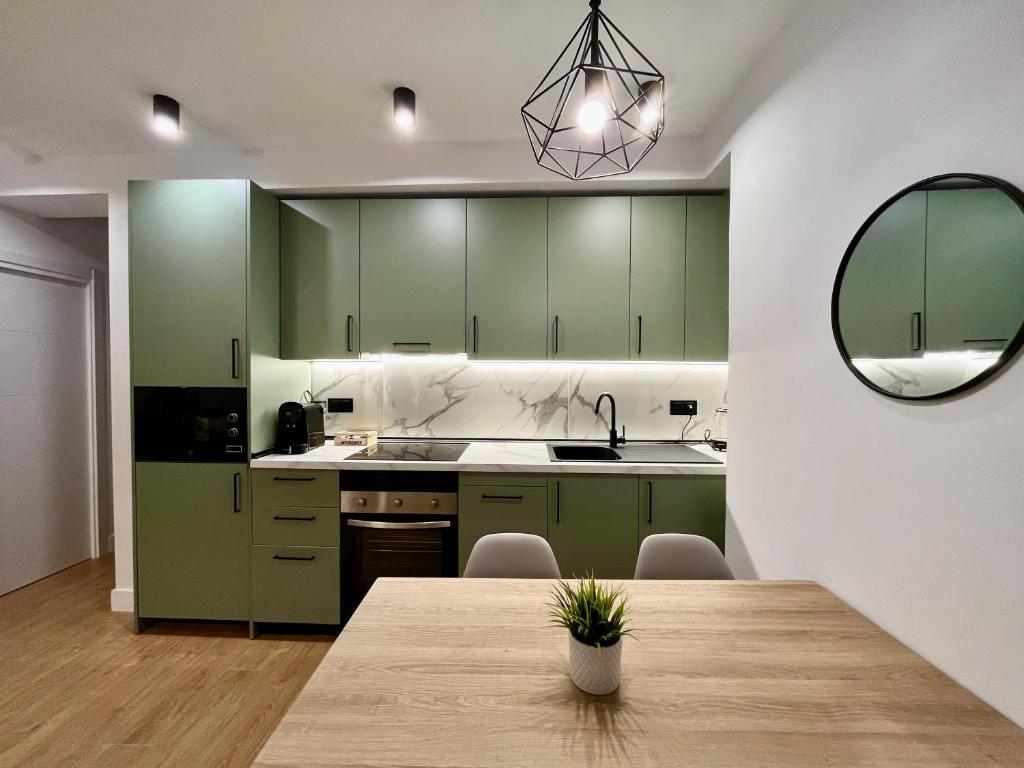 eine Küche mit grünen Schränken und einem Holztisch in der Unterkunft Piso Picasso, Modern Apartment in the Heart of Malaga City in Málaga