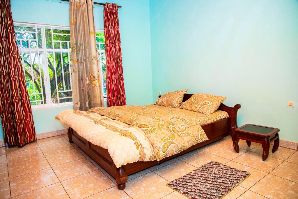 łóżko w pokoju z oknem i prześcieradłem w obiekcie PEACE Homes w mieście Kigali