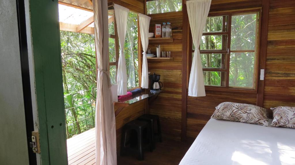 a bedroom with a bed and windows in a room at Cabanas sítio Ancestral in Morretes