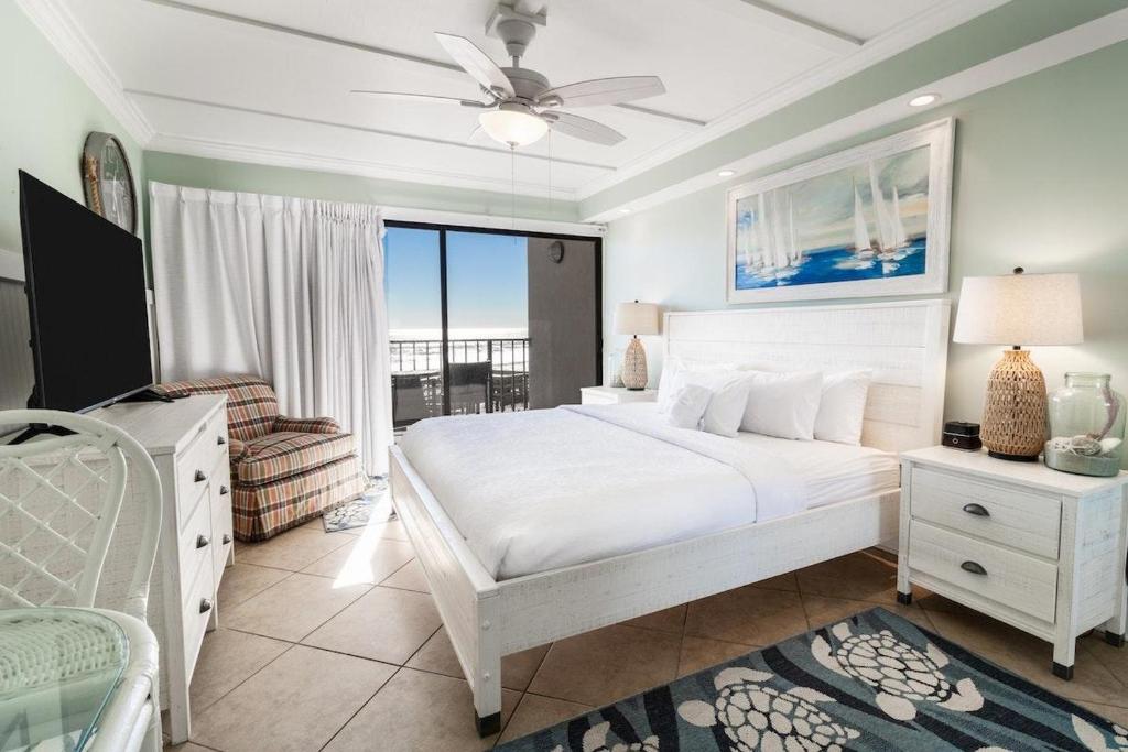 a white bedroom with a bed and a balcony at Ocean Breeze Oceanfront Tower King Room 2nd Fl in Pawleys Island