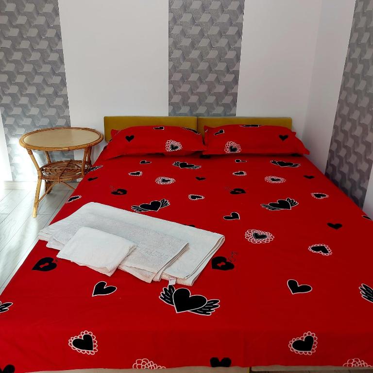 Una cama con una colcha roja con corazones. en Dayana Home en Râmnicu Vâlcea
