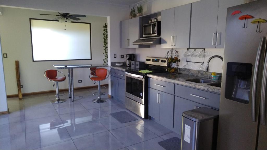 una cocina con armarios blancos y sillas rojas. en Casa ALGABELLA, en Ángeles