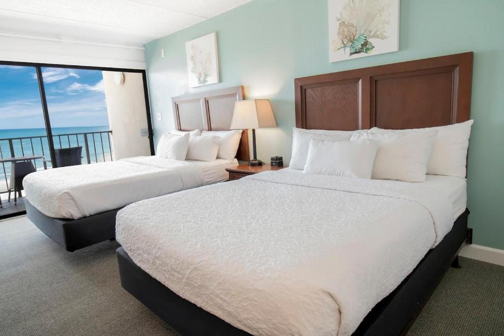 two beds in a hotel room with a balcony at Oceanfront Room 7th Floor Sleeps 4 in Pawleys Island