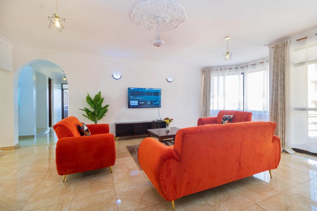 a living room with two orange chairs and a tv at 3 bedroom Nyali apartment in Mombasa