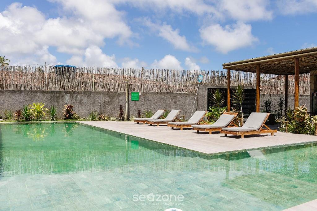 - un ensemble de chaises longues installées à côté de la piscine dans l'établissement Apto relaxante próximo a Praia do Patacho CVPE102, à Porto de Pedras