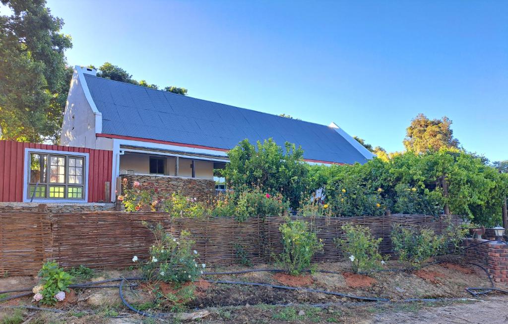 a red house with a brick fence in front of it at Goedgeloof Farm Stay in Barrydale
