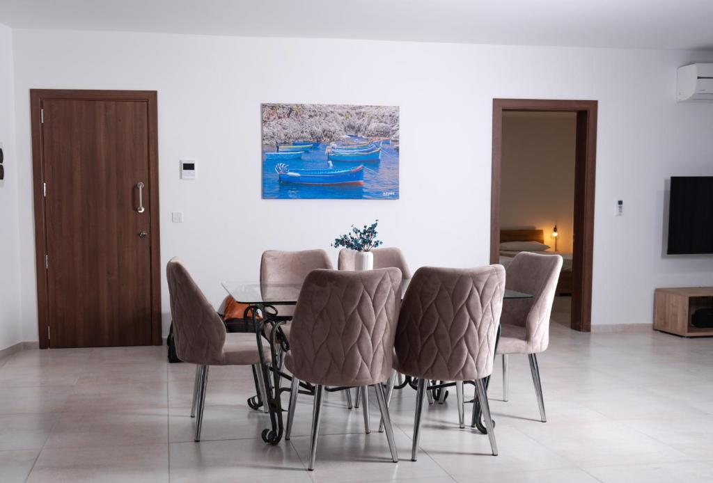 un comedor con mesa, sillas y una pintura en Azure FOUR en Żurrieq