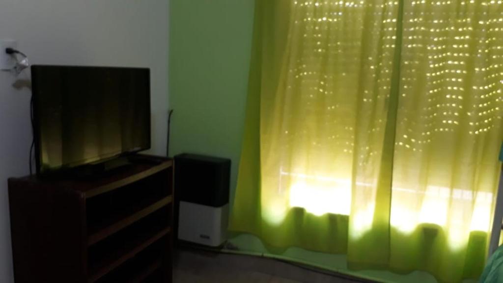 1 dormitorio con TV y cortina verde en Casa Shanti en Monte Hermoso