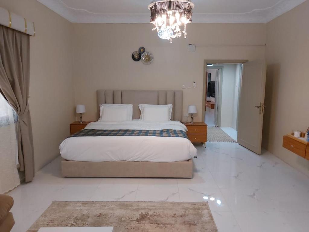 a bedroom with a large bed and a chandelier at ليالي العروبة شقة مفروشة in Riyadh