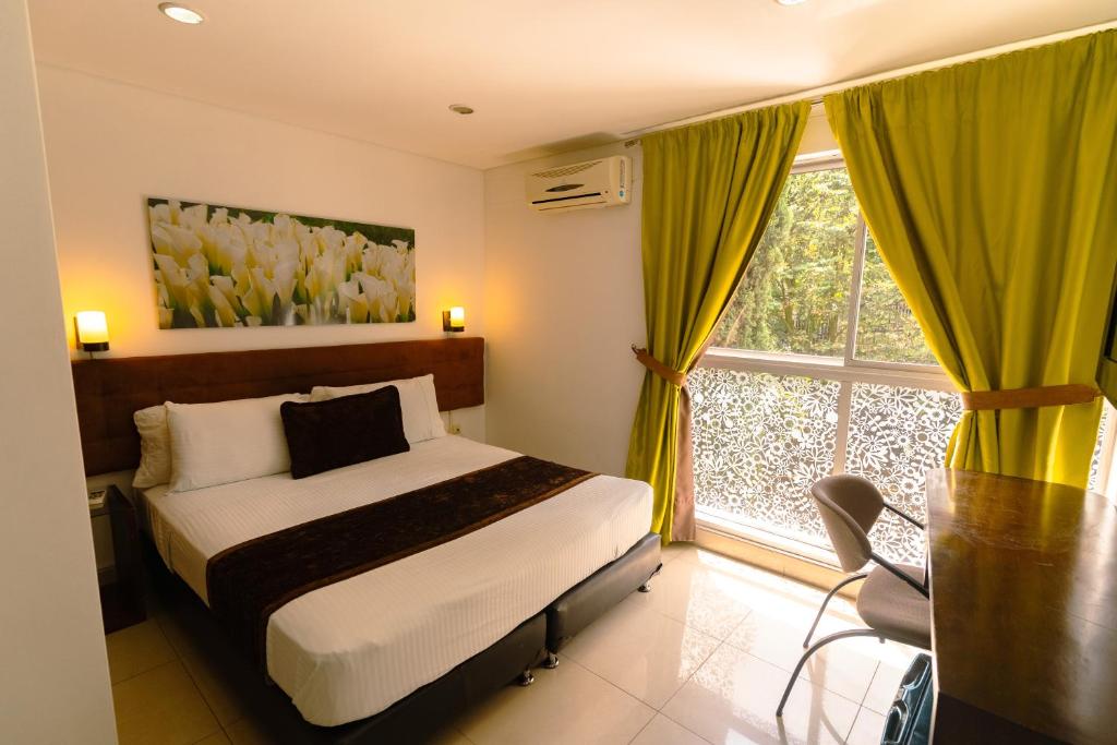 um quarto com uma cama e uma janela em Hotel Boutique las Rosas 5 G em Medellín