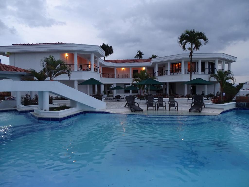 una casa grande con piscina frente a ella en Hotel Palmas De Alcalá en Playa Verde