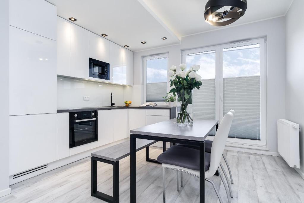 a kitchen with a table and a vase of flowers at Elite Apartments Oliwa Business Center in Gdańsk