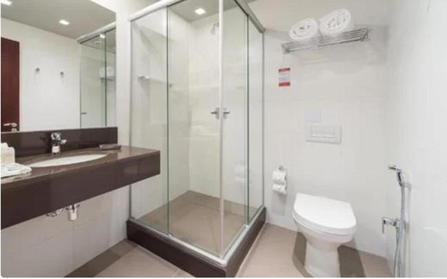 uma casa de banho com uma cabina de duche em vidro e um WC. em Hotel Laghetto Stilo Borges em Gramado