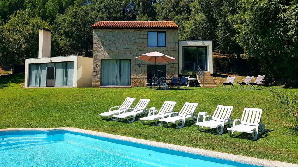 a group of white chairs and a swimming pool at Casa do Lavadouro in Paços de Gaiolo