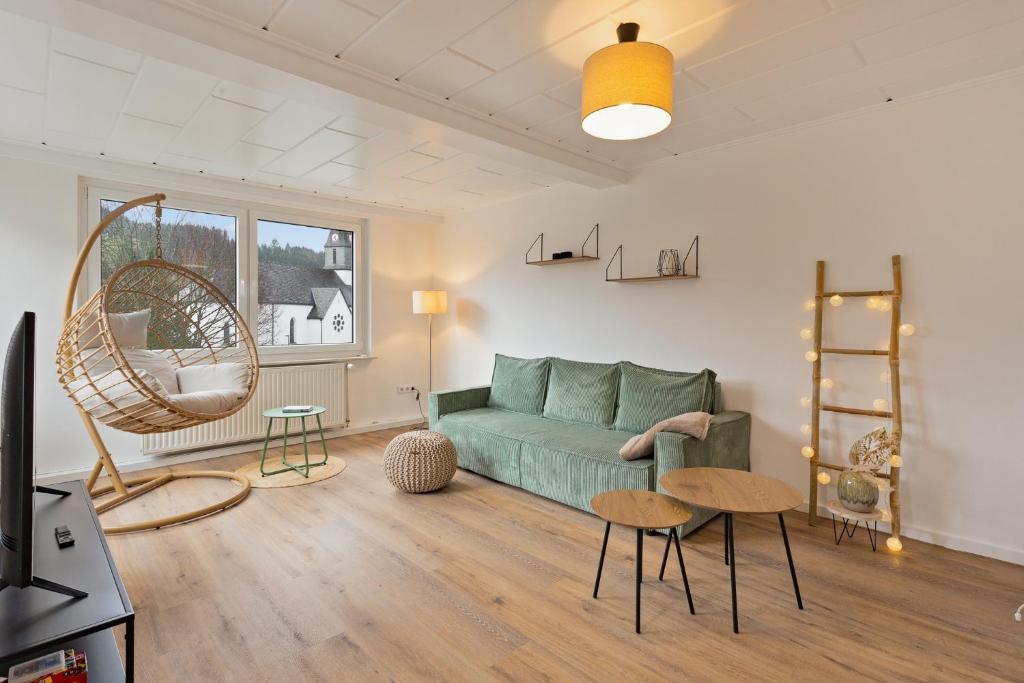 een woonkamer met een groene bank en een tafel bij GIPFELSTÜRMER Winterberg-Niedersfeld mit Infrarotsauna, Yoga, Netflix, WLAN in Winterberg