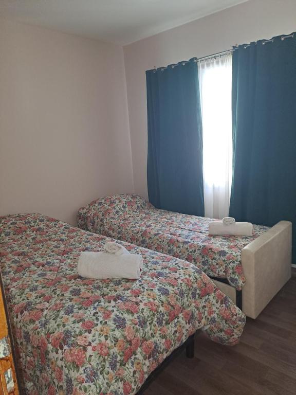 2 camas en una habitación con cortinas azules en LA LOMA AUSTRAL en El Calafate