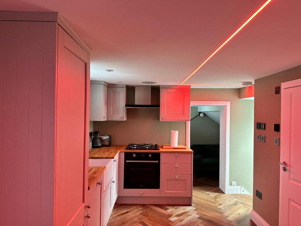 une cuisine avec des placards roses et une lumière au plafond dans l'établissement Super deluxe apartment, à Barnet