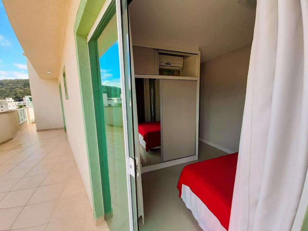Habitación pequeña con cama y puerta de cristal en Apartamento praia Bombas com 2 quartos cobertura, en Bombinhas