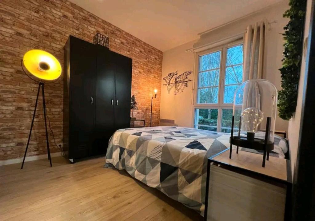 une chambre avec un lit et un mur de briques dans l'établissement APPARTEMENT IDÉALEMENT SITUE - DISNEYLAND PARIS, à Serris