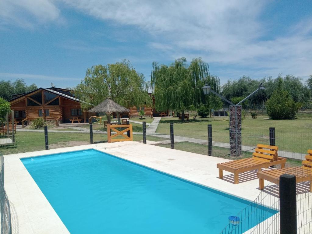 une piscine avec deux bancs et une maison dans l'établissement CABAÑAS VALLE LUNLUNTA, à Maipú