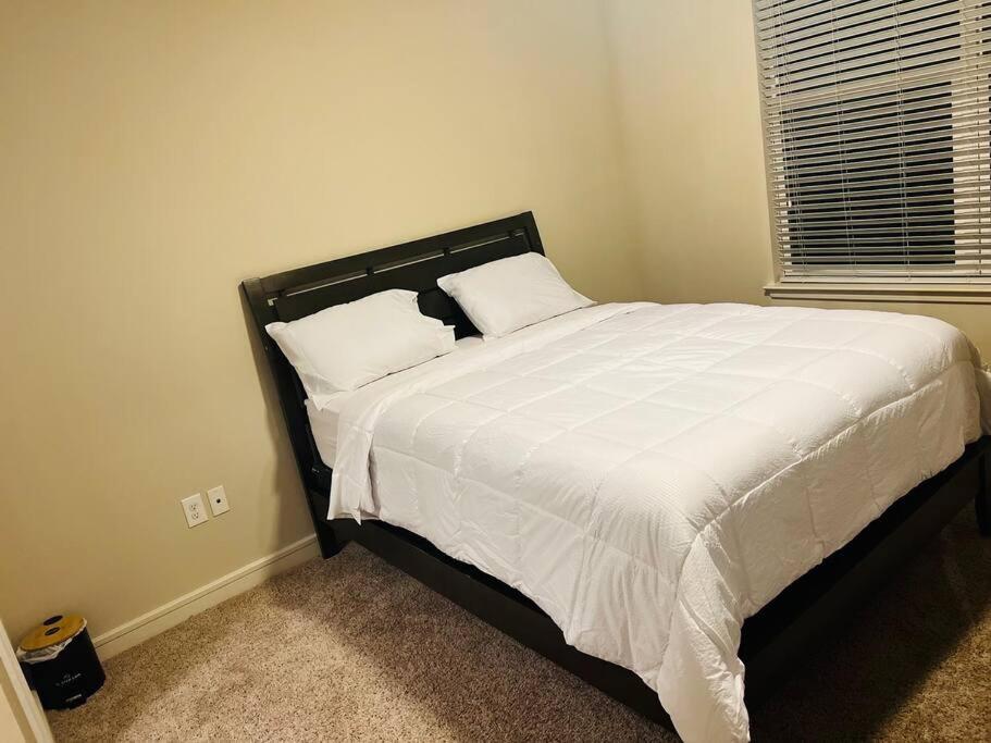 uma cama com lençóis brancos e almofadas num quarto em Home at Energy corridor em Houston