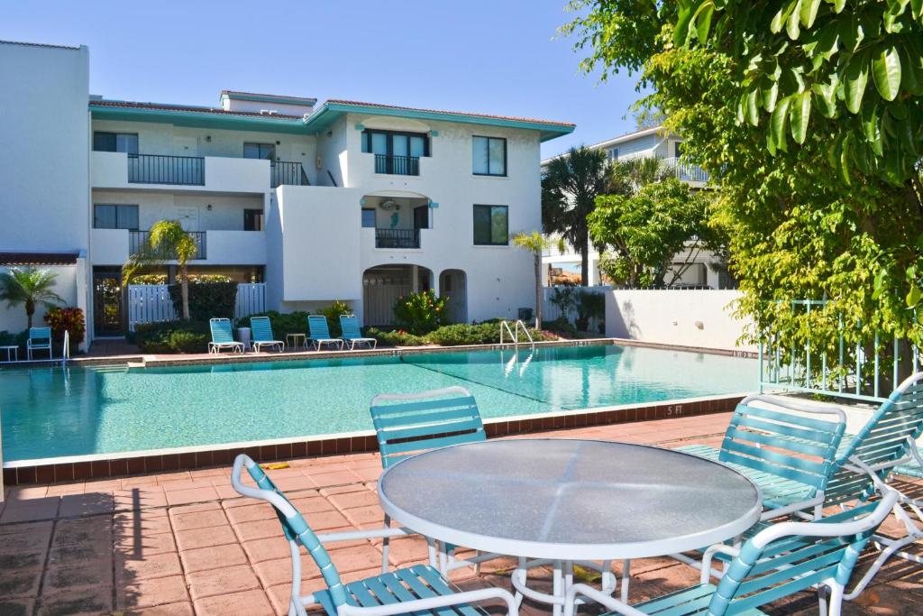 uma mesa e cadeiras ao lado de uma piscina em Ocean Park Terrace 202 em Bradenton Beach