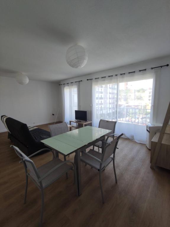 a living room with a glass table and chairs at Grand Logement à 15 min de la mer in Perpignan