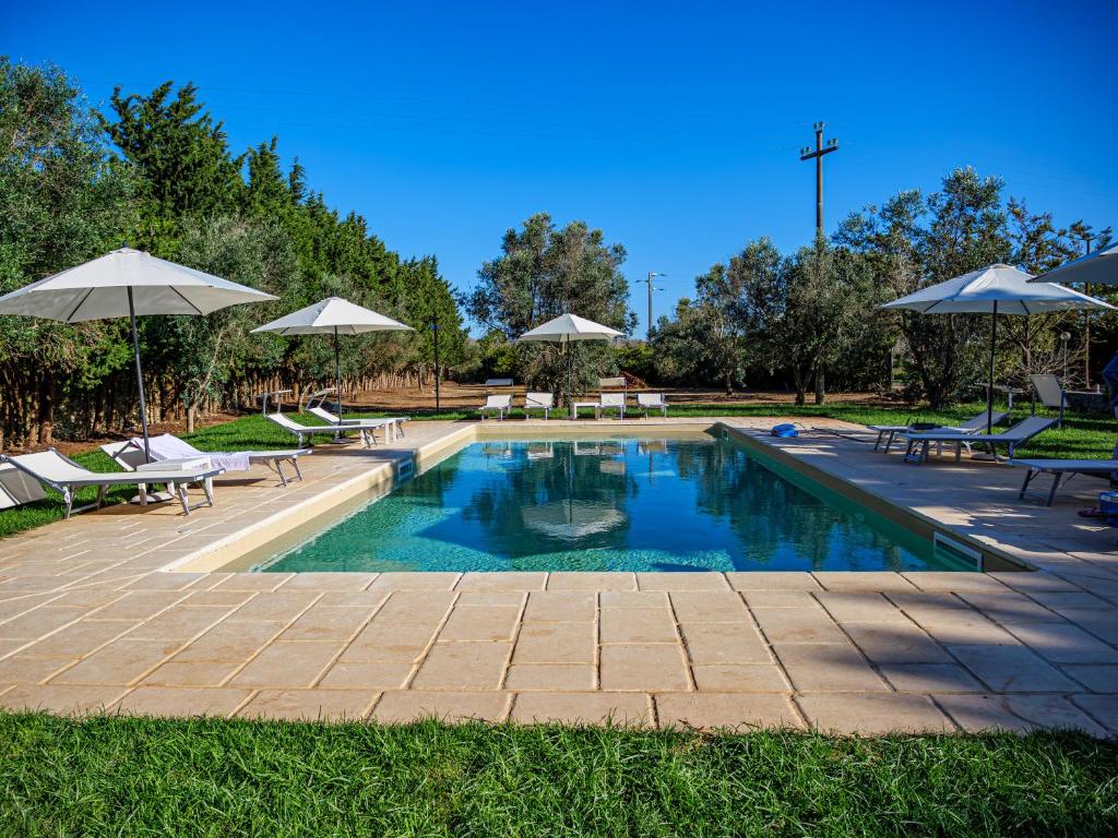 una piscina con sedie e ombrelloni in un parco di Masseria Fagà a Otranto