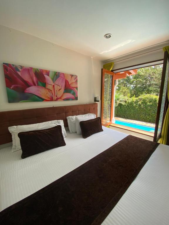 a bedroom with a large bed with a large window at Hotel Boutique las Rosas 5 G in Medellín